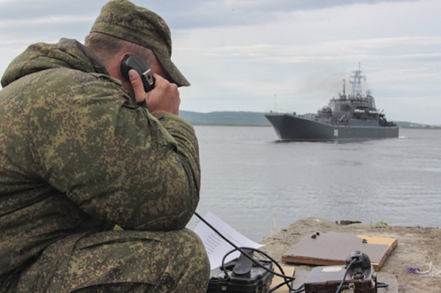 A photograph displaying an exercise taking place involving a military ship and service member.  